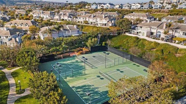 view of tennis court featuring fence and a residential view