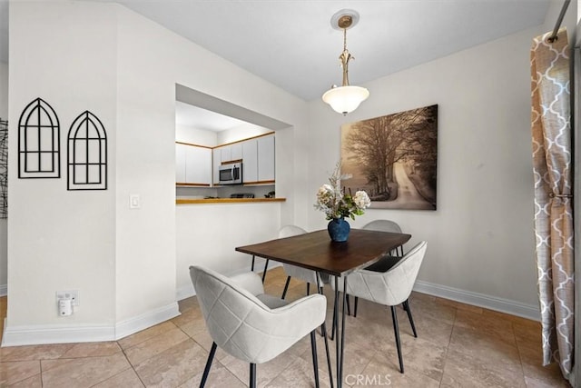 dining space featuring light tile patterned flooring and baseboards