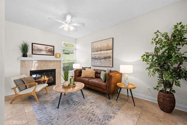 living area featuring light tile patterned flooring, baseboards, a ceiling fan, and a tile fireplace