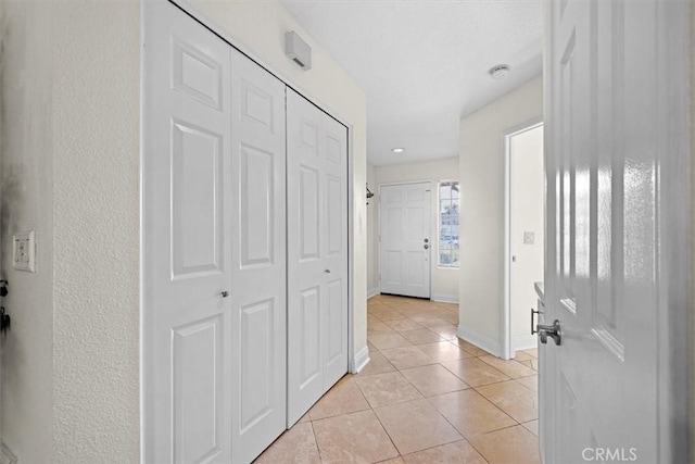 corridor with light tile patterned floors and baseboards