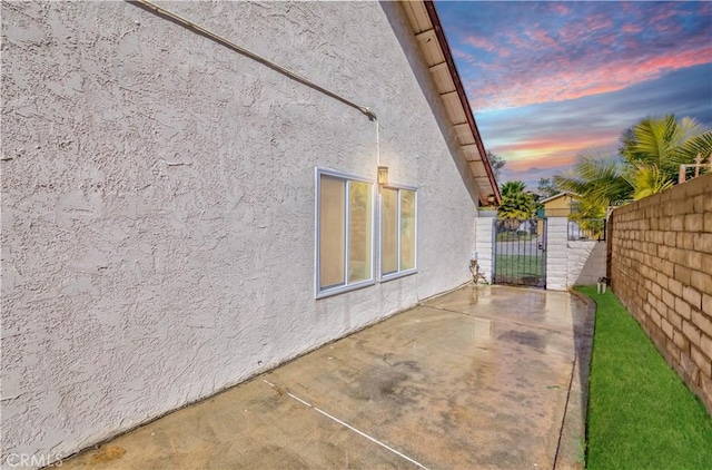 view of side of home featuring a patio, fence, and stucco siding