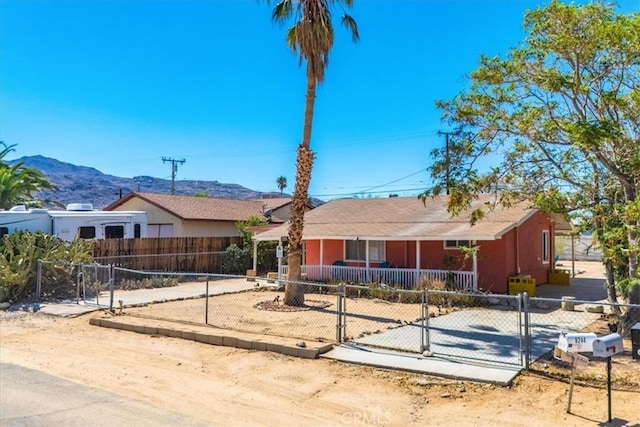 single story home with covered porch, a fenced front yard, and a mountain view