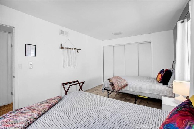 bedroom with a closet, visible vents, and tile patterned floors