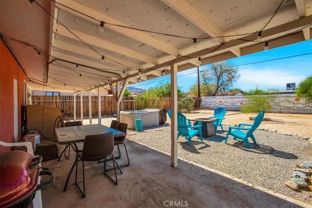 view of patio / terrace featuring outdoor dining space, a fenced backyard, a fire pit, and a hot tub