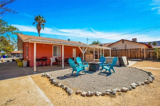 back of property with an outdoor fire pit, fence, and a patio