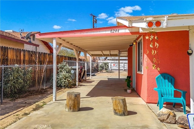 view of patio / terrace featuring driveway, fence, and a carport