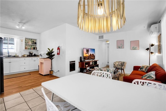 interior space featuring light wood-type flooring, a wall mounted air conditioner, and visible vents