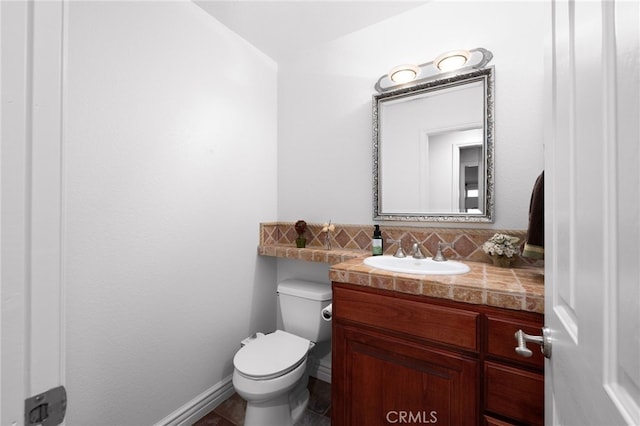 half bathroom with toilet, tasteful backsplash, baseboards, and vanity