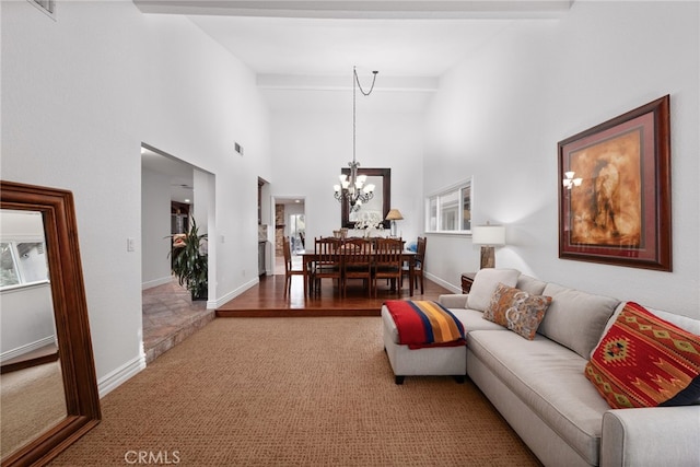 living area featuring beam ceiling, a high ceiling, baseboards, and an inviting chandelier