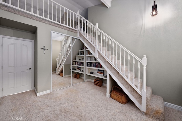 stairs featuring carpet floors, a high ceiling, and baseboards