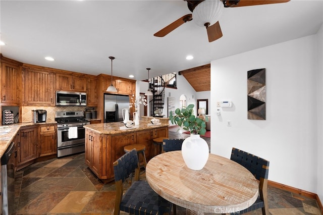 kitchen featuring stainless steel appliances, decorative backsplash, a center island, and stone tile floors