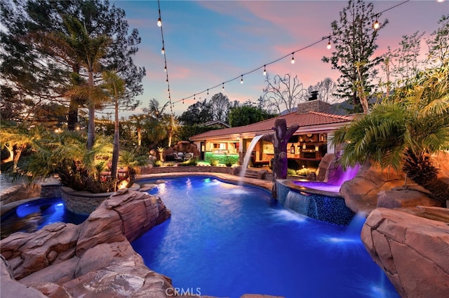 pool at dusk with an in ground hot tub and an outdoor pool