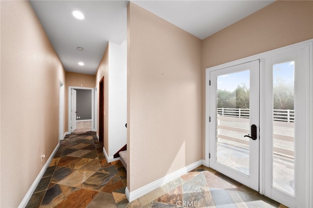 doorway featuring recessed lighting, stone tile flooring, baseboards, and stairs