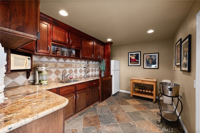 bar with white appliances, a sink, baseboards, decorative backsplash, and stone finish flooring