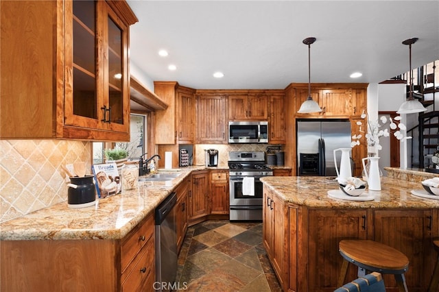 kitchen featuring brown cabinets, stone tile flooring, appliances with stainless steel finishes, glass insert cabinets, and a sink