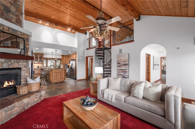 living area featuring arched walkways, wooden ceiling, rail lighting, a fireplace, and high vaulted ceiling