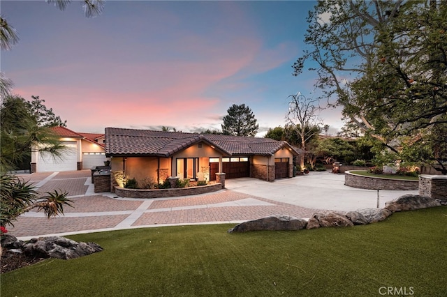 view of front facade featuring a tile roof, a yard, a garage, stone siding, and driveway