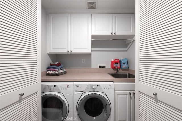 washroom with cabinet space, washing machine and dryer, visible vents, and a sink