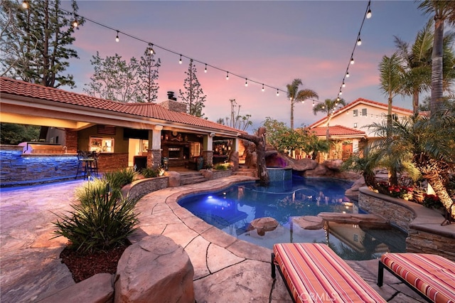 pool at dusk featuring outdoor dry bar, a patio, and a pool with connected hot tub