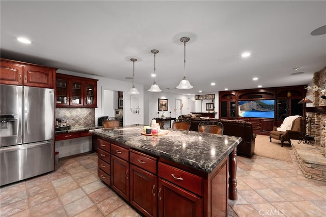 kitchen featuring open floor plan, backsplash, stainless steel fridge, and a center island