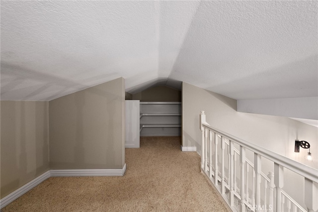 bonus room featuring vaulted ceiling, a textured ceiling, carpet flooring, and baseboards