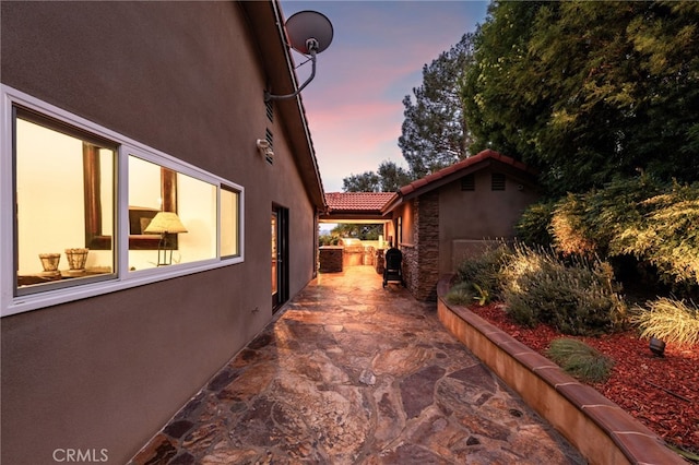 property exterior at dusk with a patio area and stucco siding