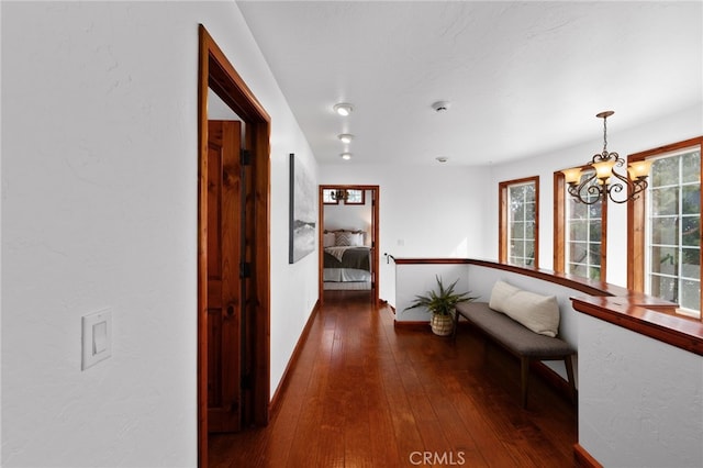 corridor with hardwood / wood-style flooring and a notable chandelier