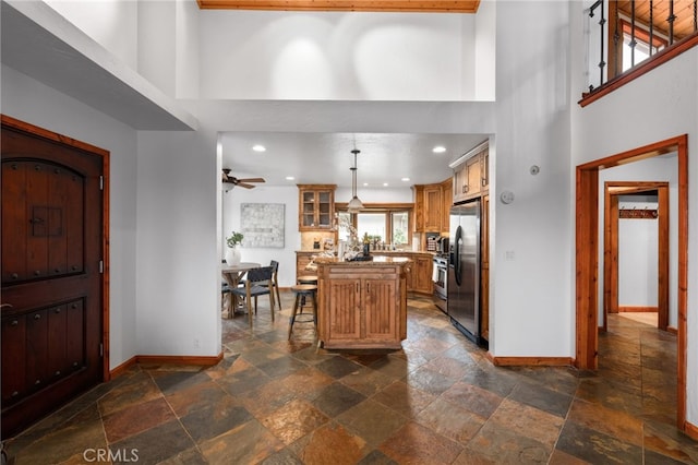 foyer with recessed lighting, stone tile flooring, a high ceiling, and baseboards