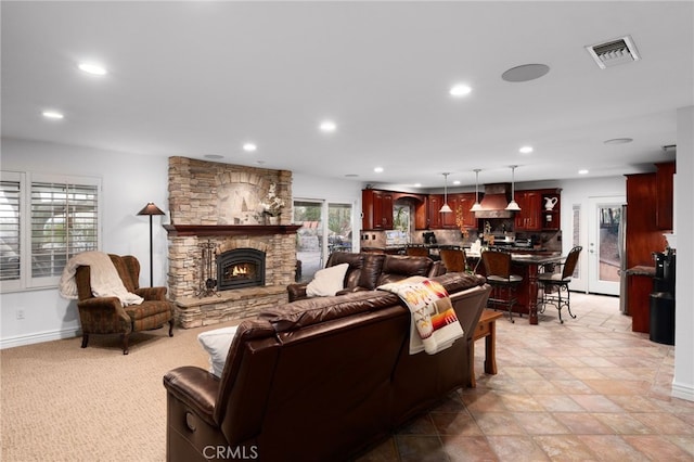 living room with recessed lighting, visible vents, a stone fireplace, and baseboards