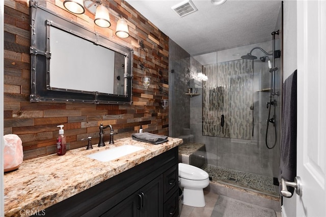 full bathroom featuring visible vents, toilet, a textured ceiling, vanity, and a shower stall