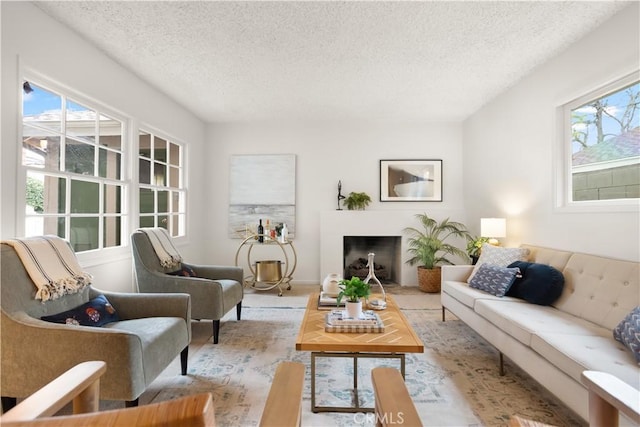 living area with a textured ceiling, a fireplace, and a wealth of natural light