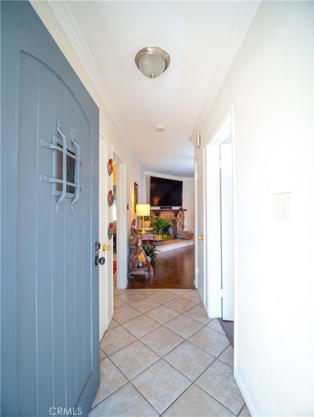 hall featuring light tile patterned floors and crown molding