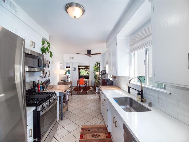 kitchen featuring decorative backsplash, appliances with stainless steel finishes, light countertops, white cabinetry, and a sink