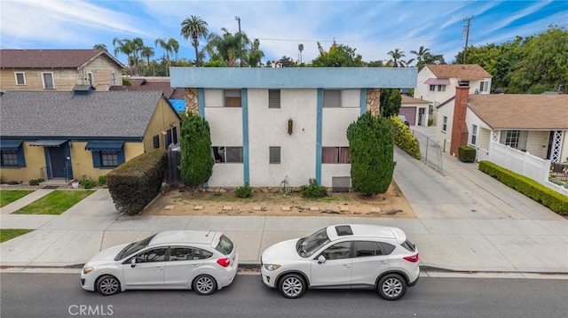 view of property with a residential view, fence, and stucco siding