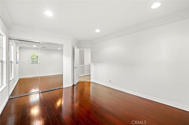 unfurnished bedroom with recessed lighting, wood finished floors, baseboards, ornamental molding, and a closet