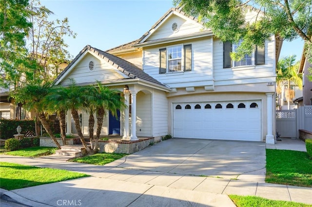 traditional home featuring driveway, an attached garage, and fence