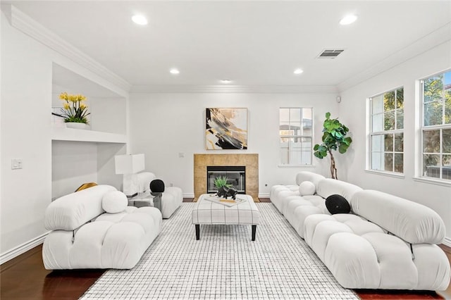 living room with baseboards, visible vents, ornamental molding, and wood finished floors