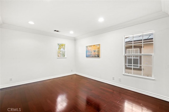 spare room with ornamental molding, visible vents, baseboards, and wood finished floors