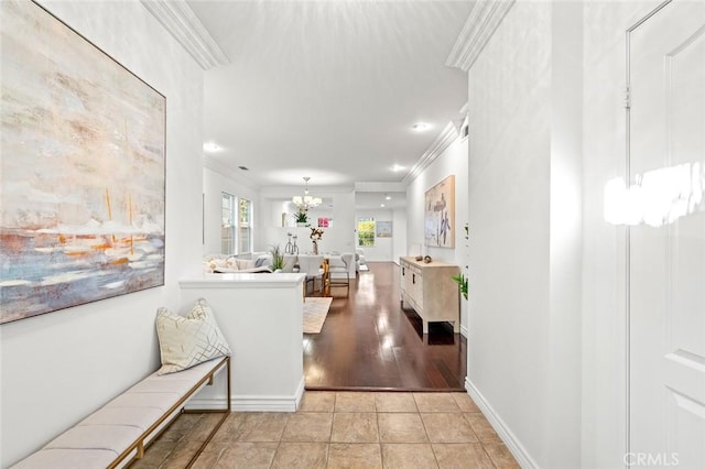 hallway featuring baseboards, ornamental molding, light tile patterned flooring, and a notable chandelier