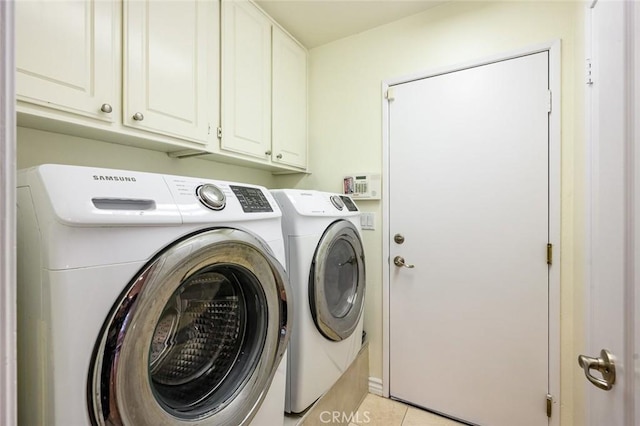 laundry room featuring washing machine and dryer, cabinet space, and light tile patterned flooring