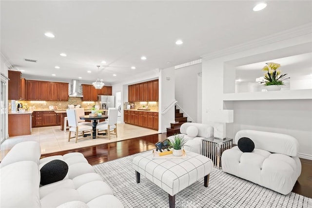 living room featuring light wood finished floors, stairs, ornamental molding, and recessed lighting