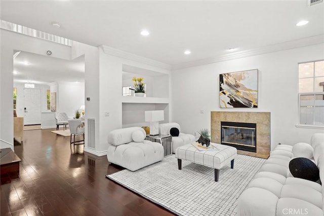 living area with ornamental molding, recessed lighting, a tiled fireplace, and wood finished floors