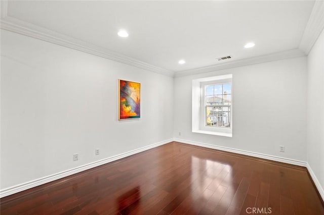 spare room with visible vents, crown molding, baseboards, and wood finished floors