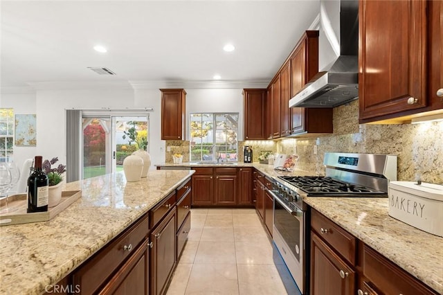 kitchen with visible vents, wall chimney exhaust hood, light stone counters, backsplash, and gas stove