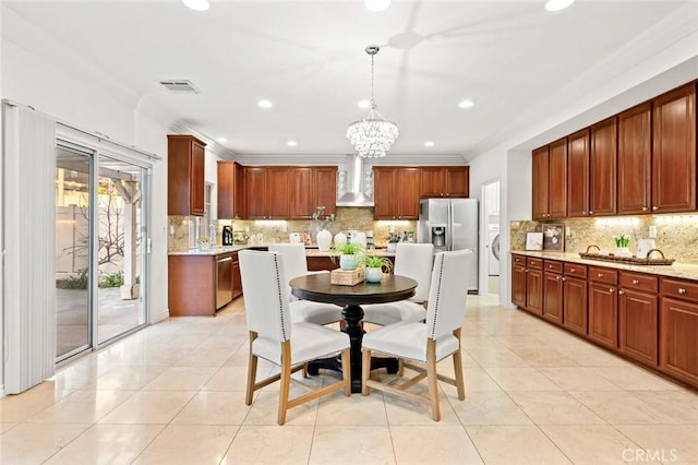 kitchen with a chandelier, wall chimney exhaust hood, light tile patterned flooring, and stainless steel appliances