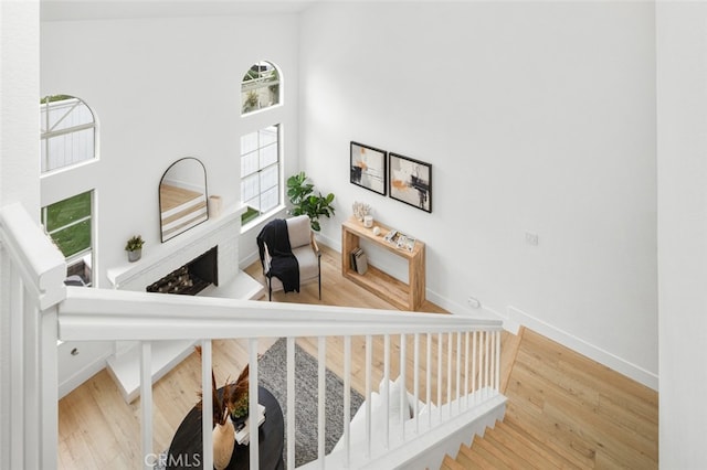 stairway featuring a high ceiling, wood finished floors, and baseboards