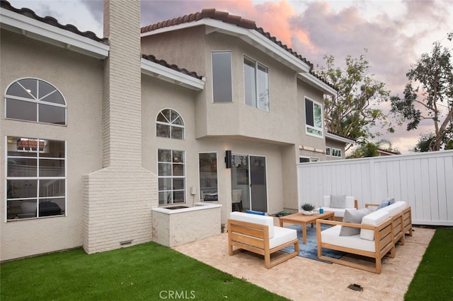 back of property at dusk featuring a patio area, fence, an outdoor living space, and stucco siding