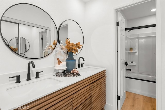 bathroom featuring double vanity, a sink, shower / tub combination, and wood finished floors