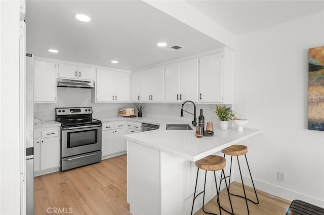 kitchen with visible vents, appliances with stainless steel finishes, a sink, a peninsula, and under cabinet range hood