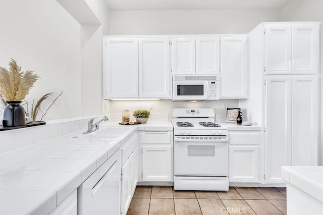 kitchen featuring tile countertops, white appliances, and white cabinetry